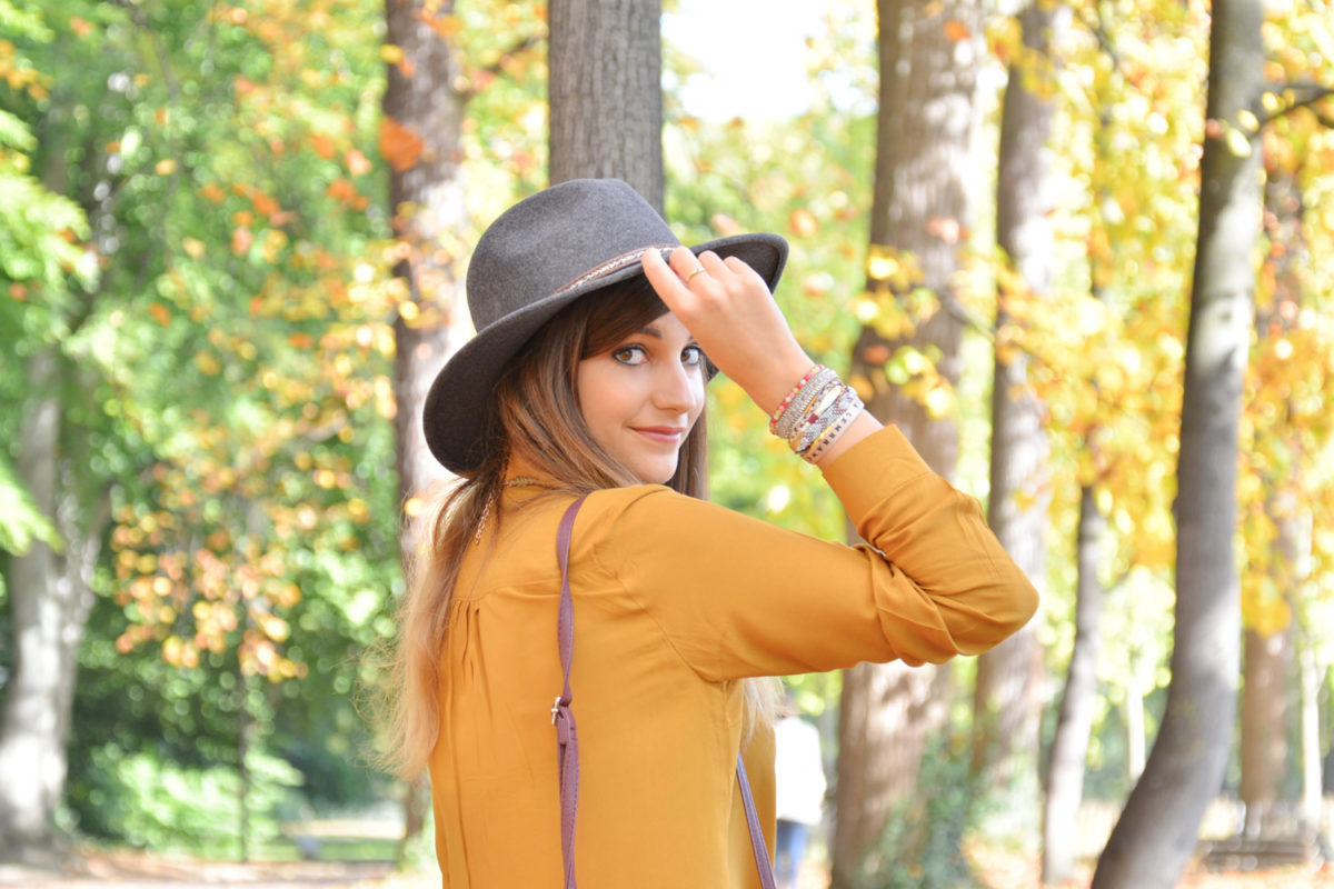 Look automne : chemise jaune moutarde, jean destroy, chapeau gris et boots bordeaux